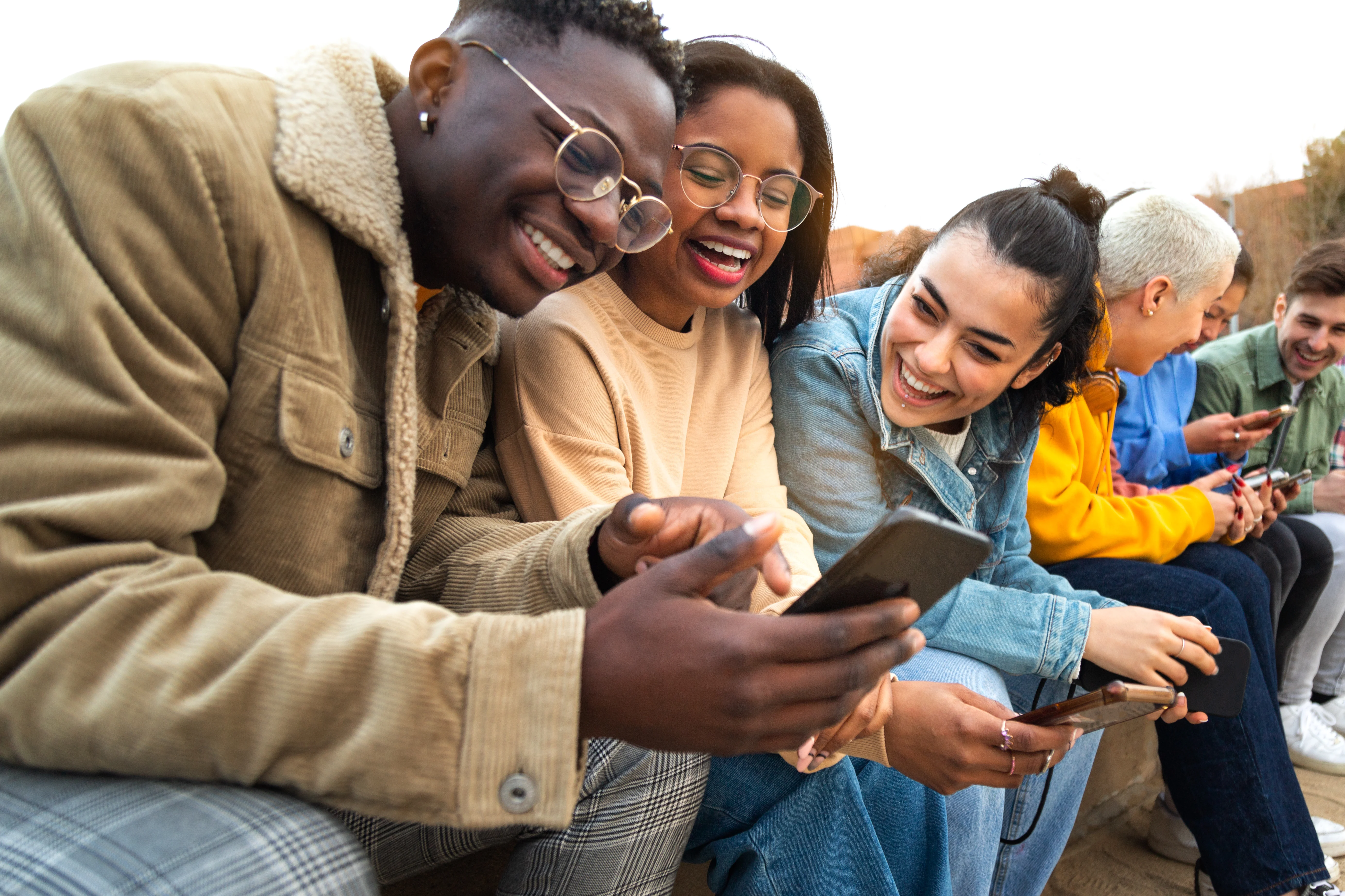 group of friends laughing and leaning over to look at a phone