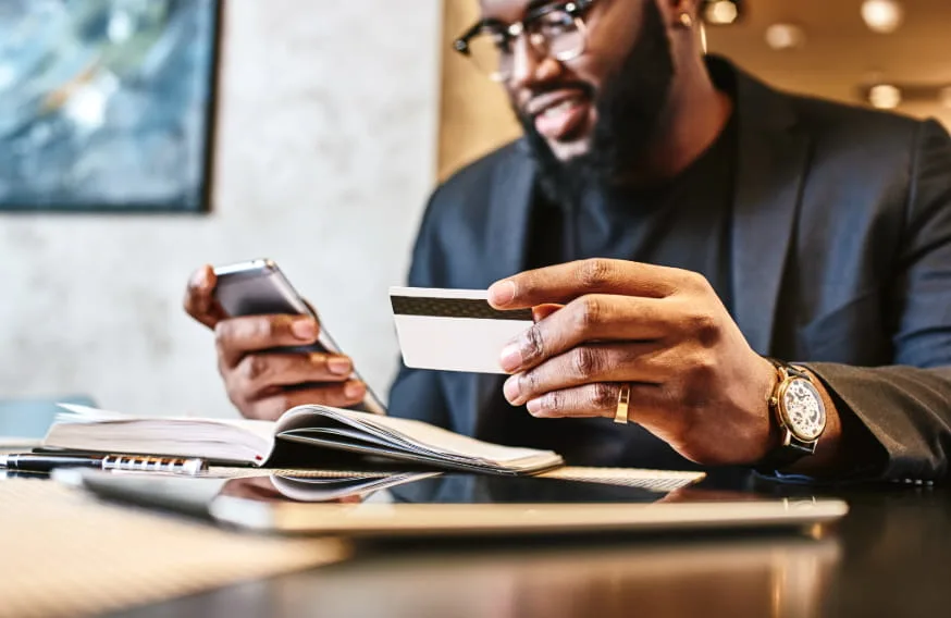 man hold credit card and phone staring down at screen