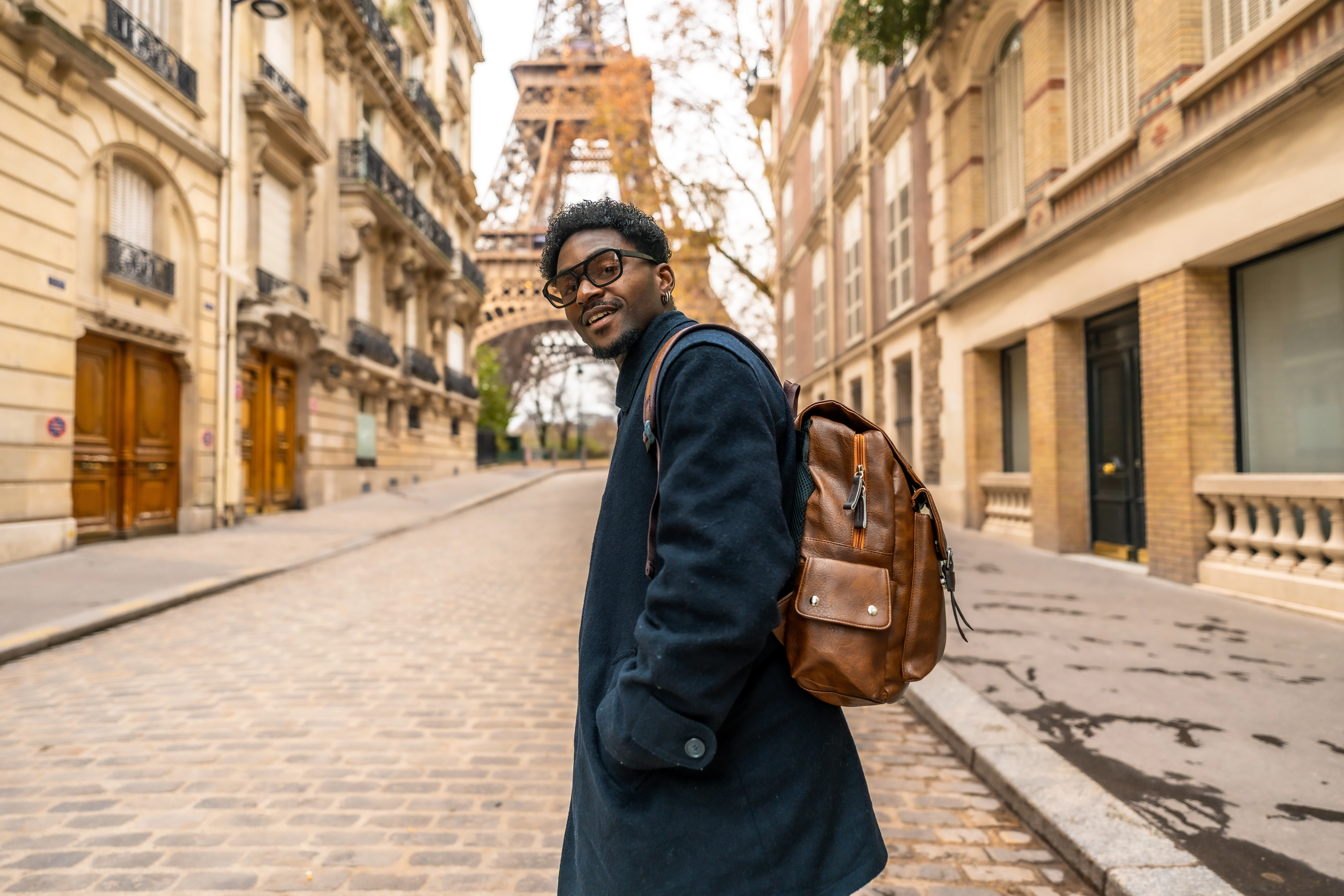 man with backpack in front of Eiffel Tower