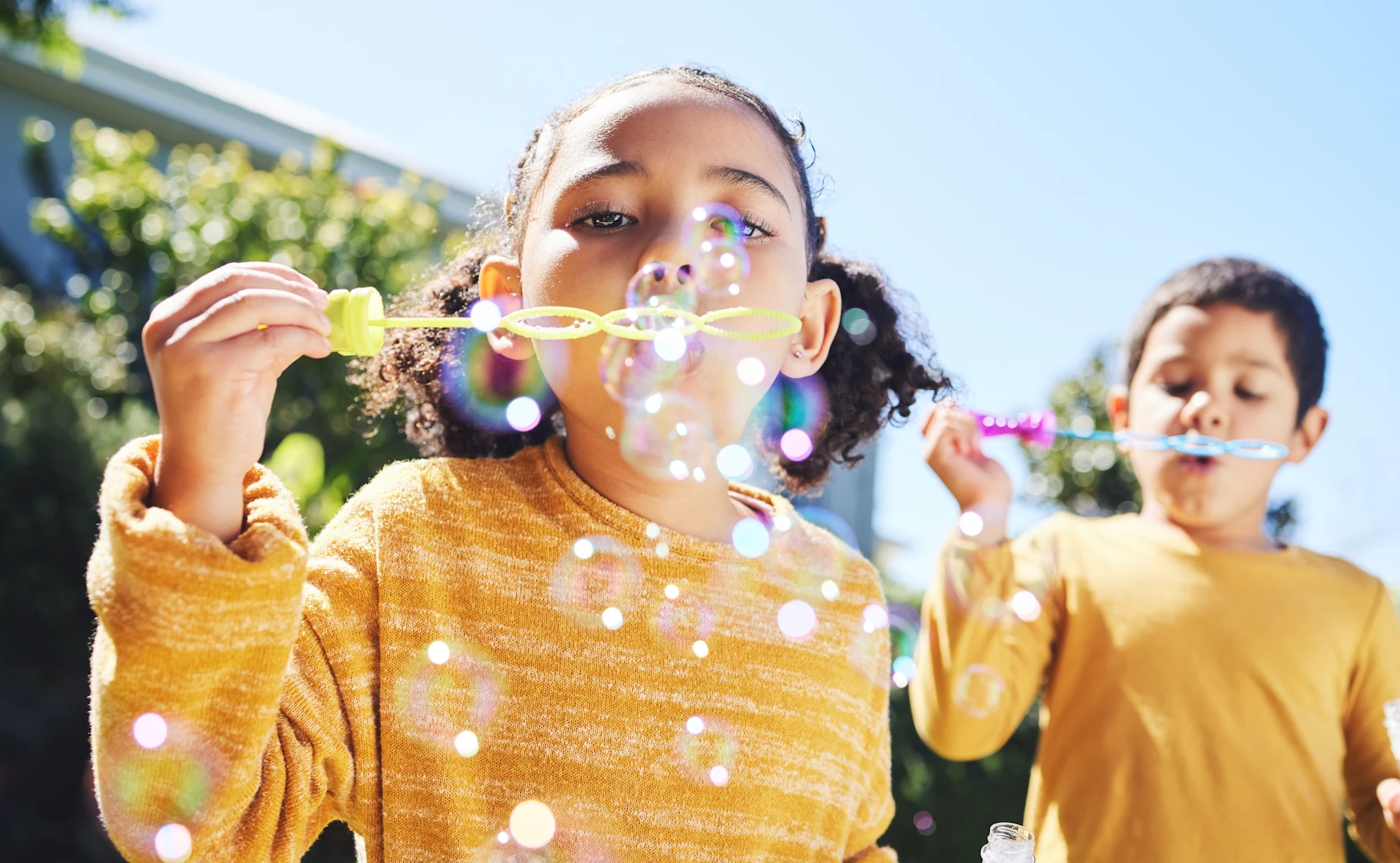 two young children blowing bubbles in their backyard