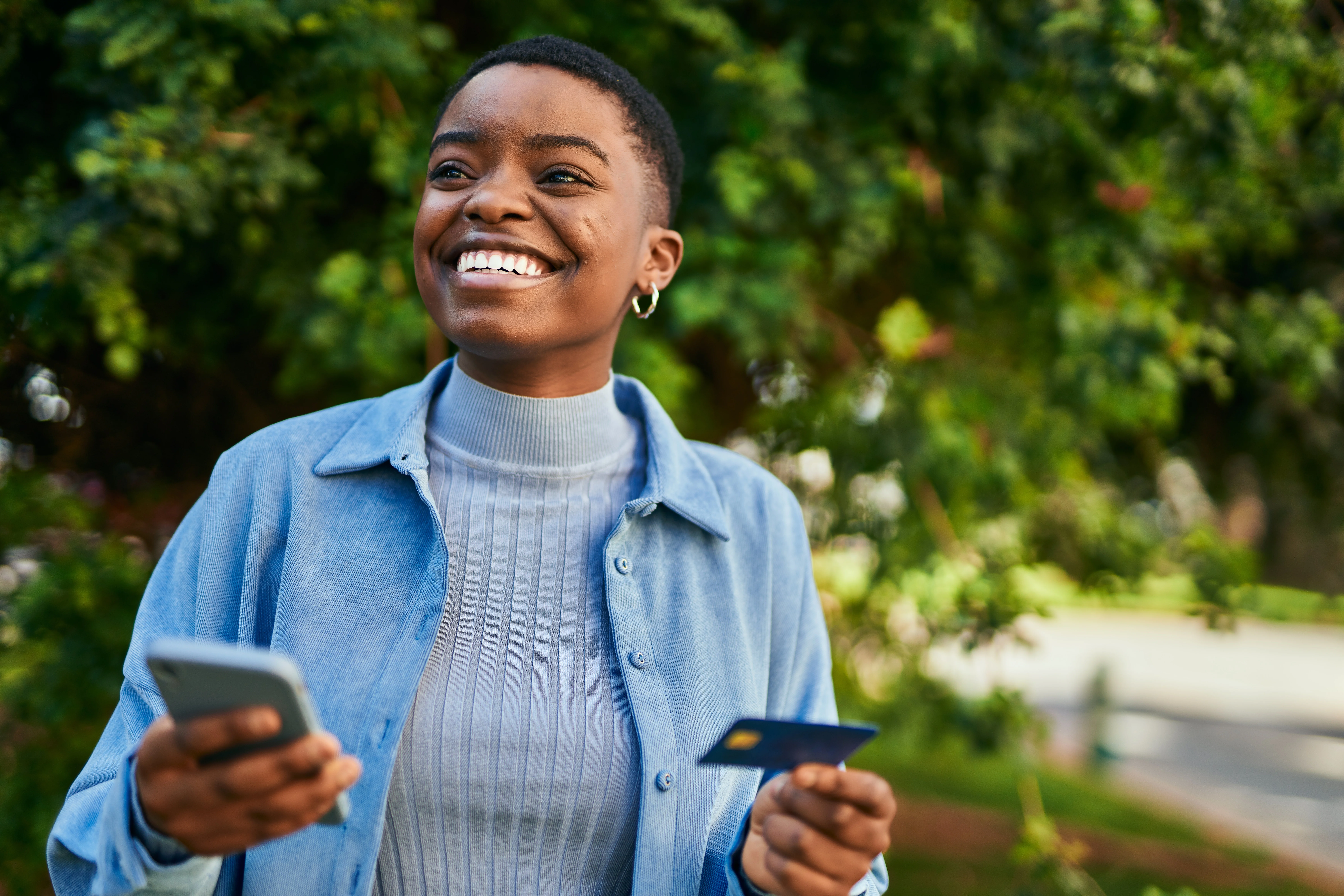 woman smiling with short hair holding a phone and credit card.jpeg