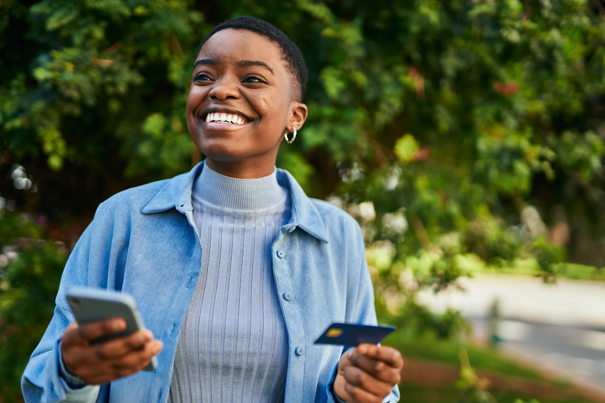 woman smiling with short hair holding a phone and credit card.jpeg