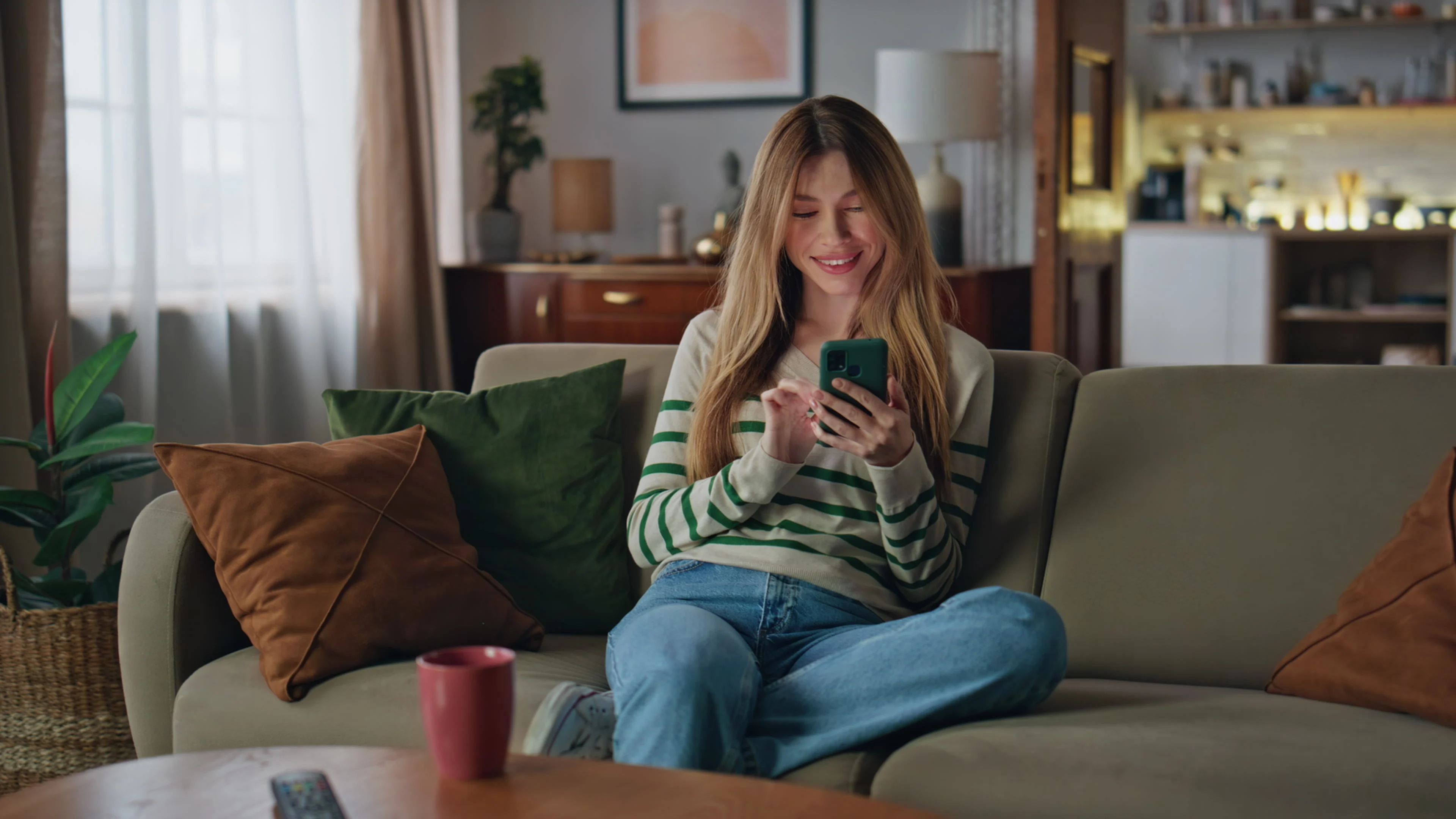 woman sitting on coach shopping on her phone