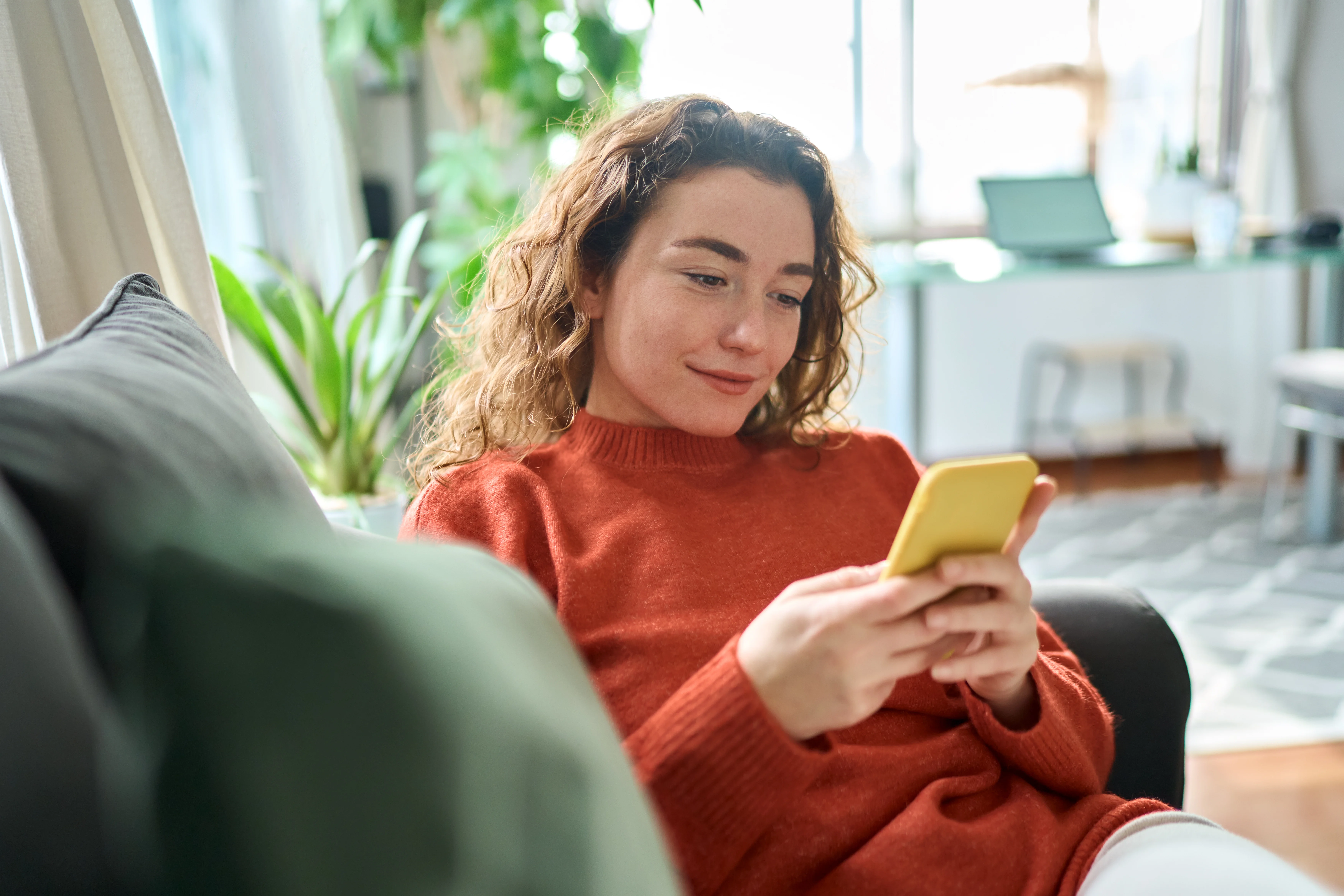 woman on her couch shopping on phone
