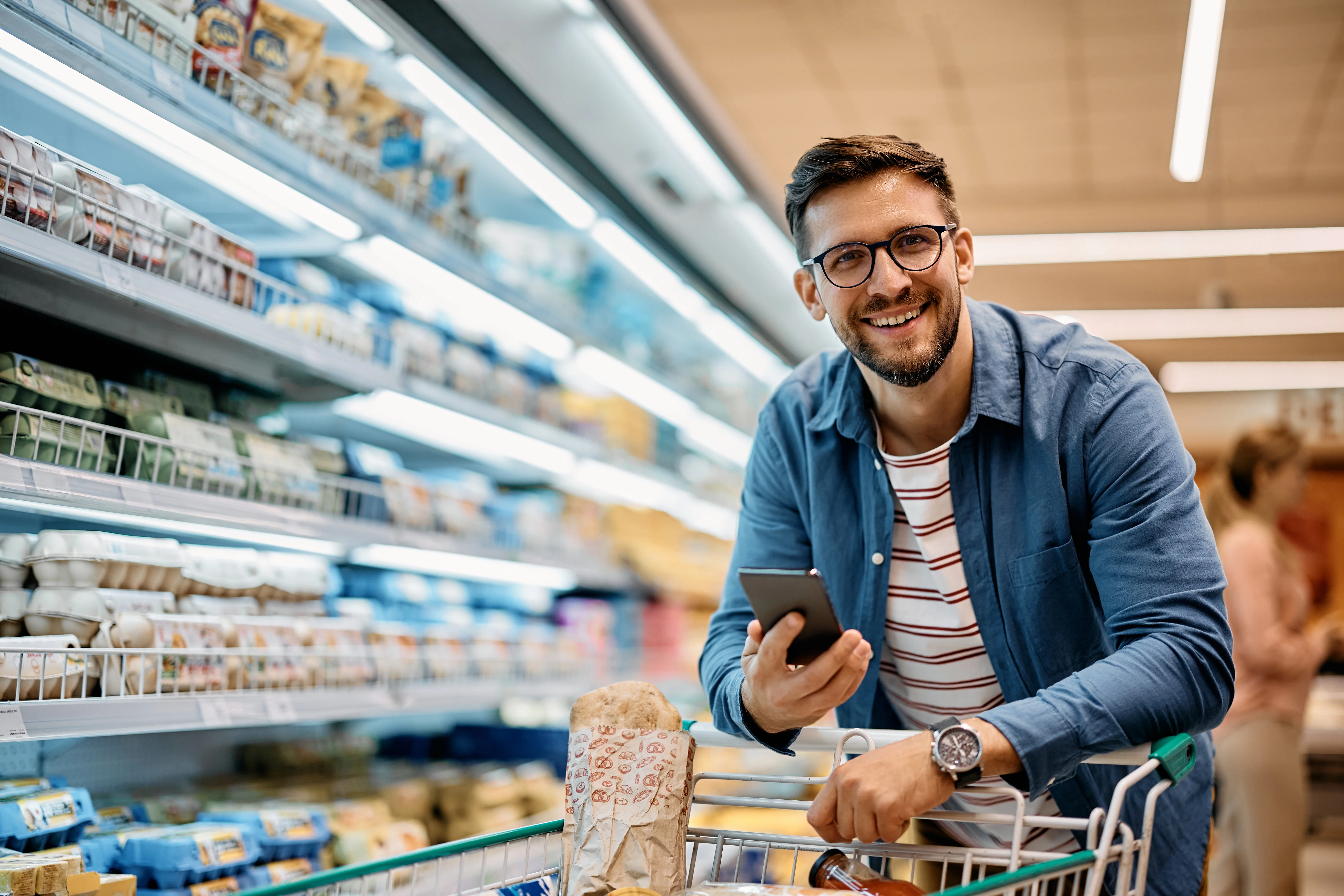 man smiling at camera while shopping with his phone