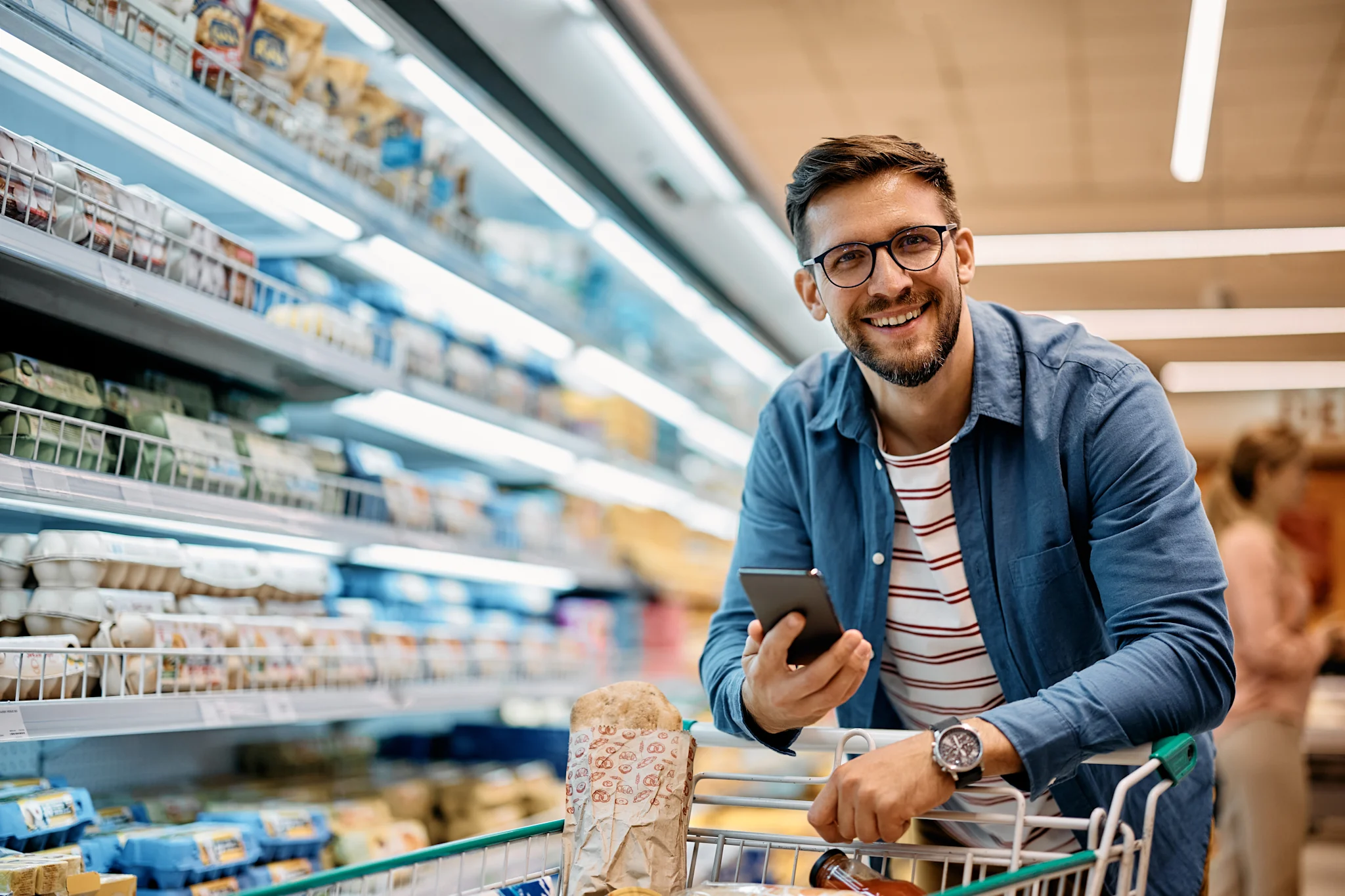 man smiling at camera while shopping with his phone