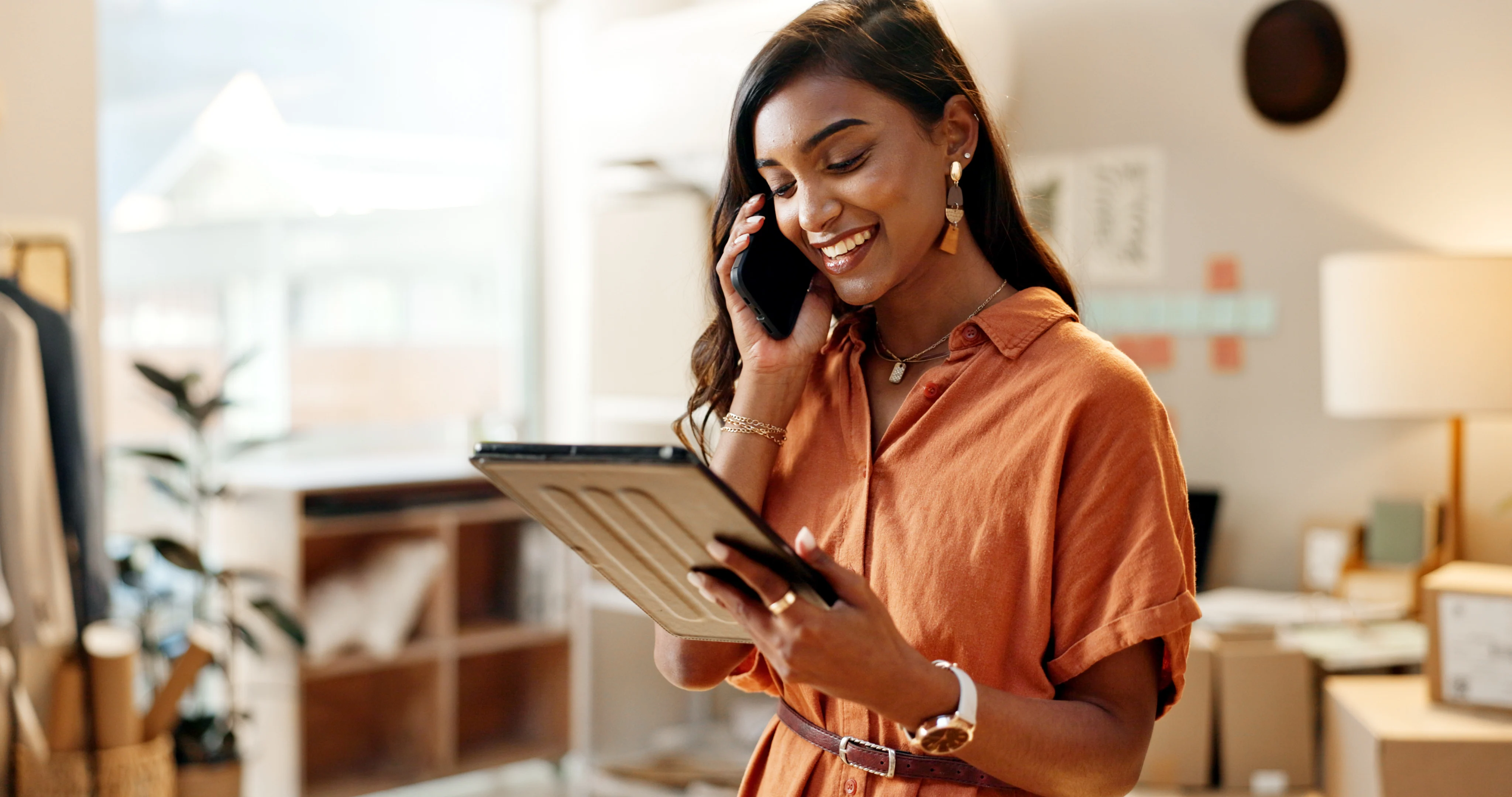 woman smiling staring at a tablet and speaking on the phone