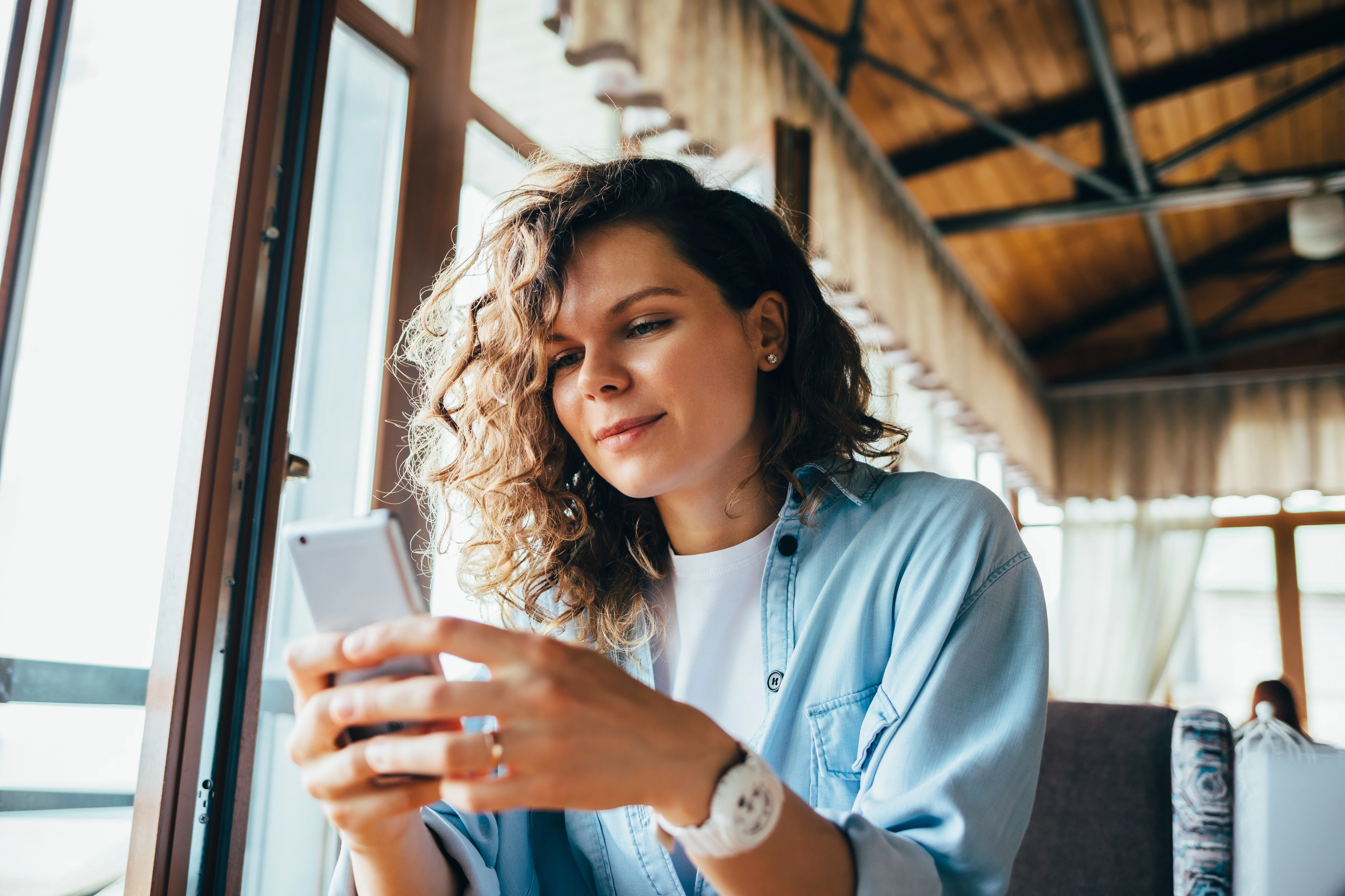 woman with curly hair leaning over her phone
