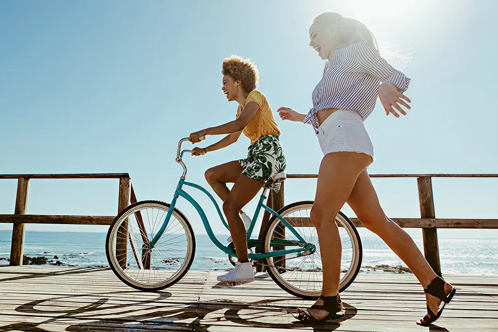 Zwei lachende Mädchen fahren mit dem Fahrrad am Pier