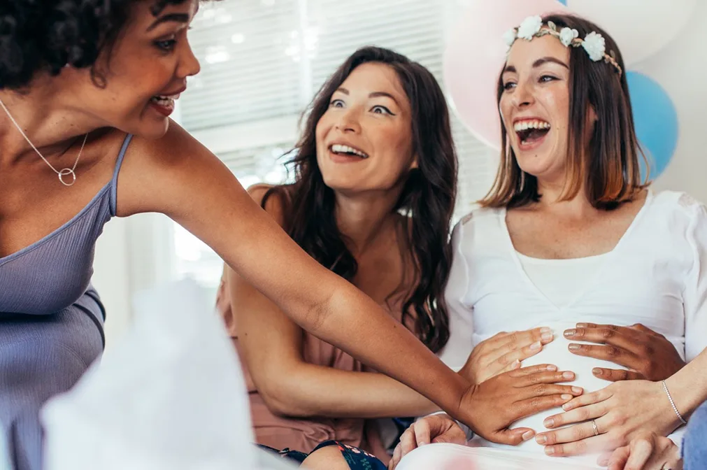 Drei Frauen halten eine schwangere Frau am Bauch