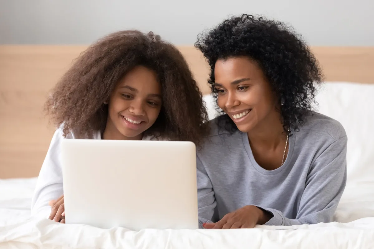 Lachende Mutter mit ihrer Tochter, die auf der Couch sitzt
