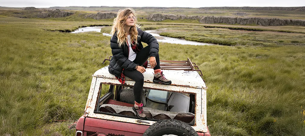 Mädchen sitzt auf dem Dach eines Geländewagens