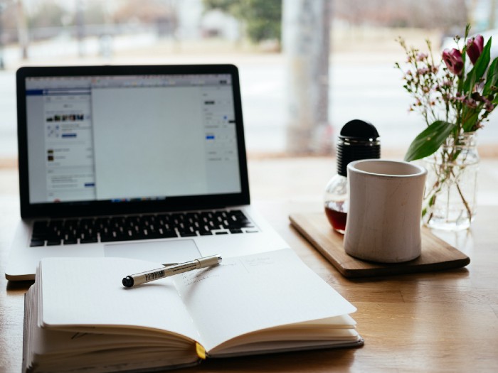Apple laptop and an open notebook on a desk