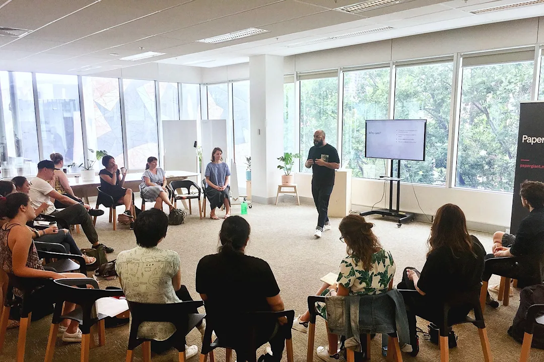 Ernez explaining a workshop activity to a group of people sat in a semi-circle