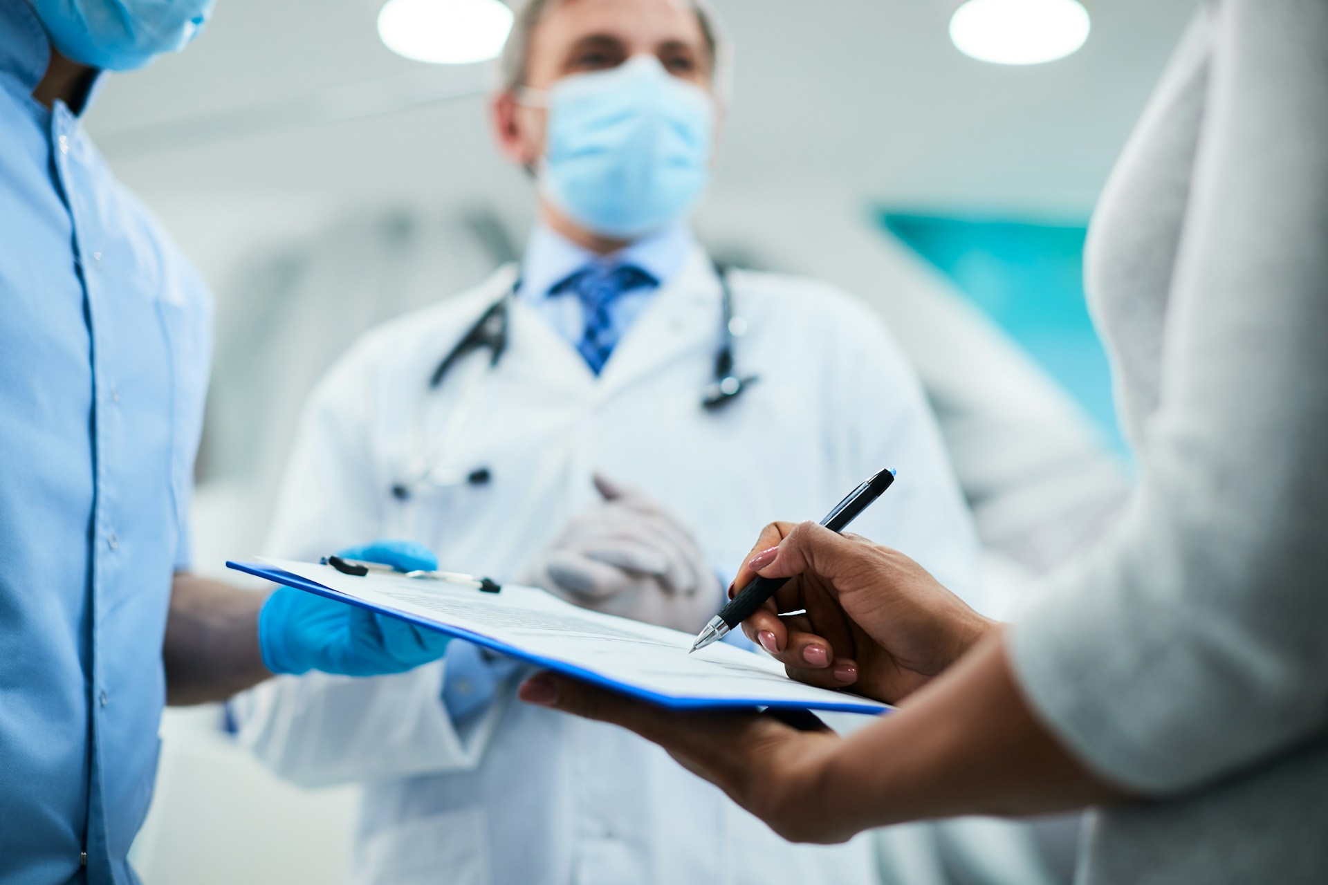 A photograph of a professional completing a paper form in a healthcare setting