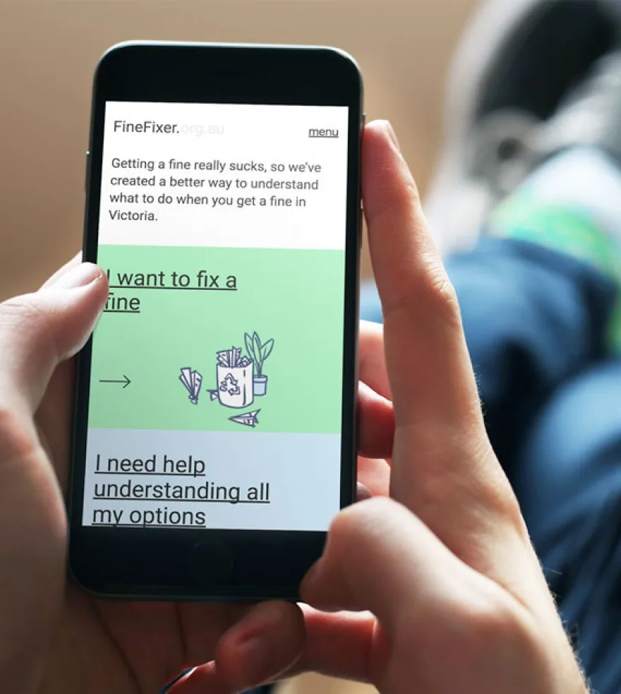 A photo of someone holding a mobile phone. They are looking at the Fine Fixer website.
