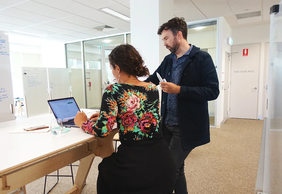 Two designers discuss a working document around a laptop