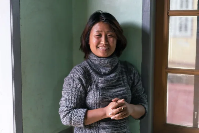 Chin woman smiling with hands clasped in front of her