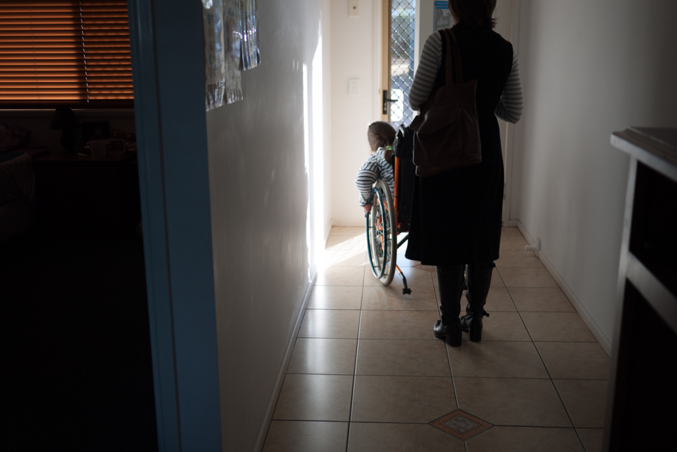 A wheelchair user leaving their house with their friend behind them