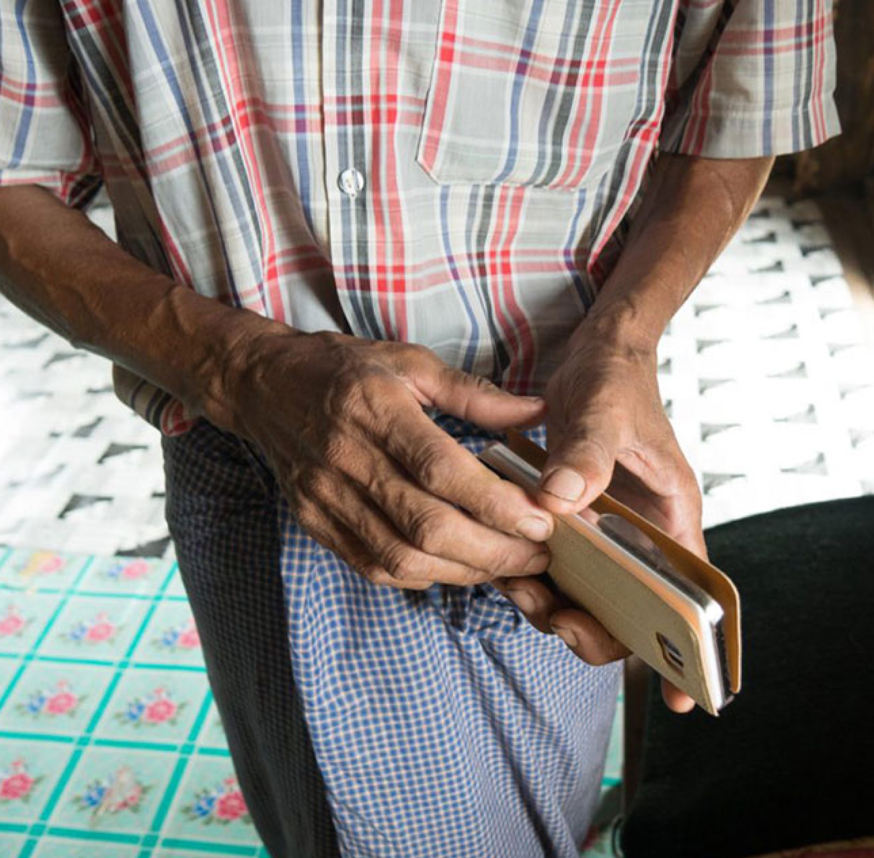 A man holds his phone out in front of him. 