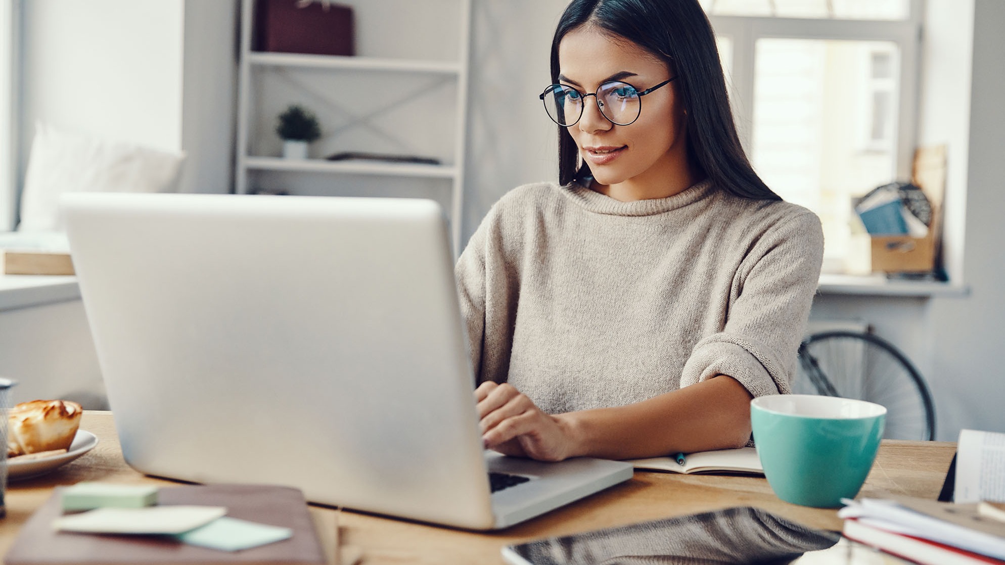 young woman with glasses working on a laptop