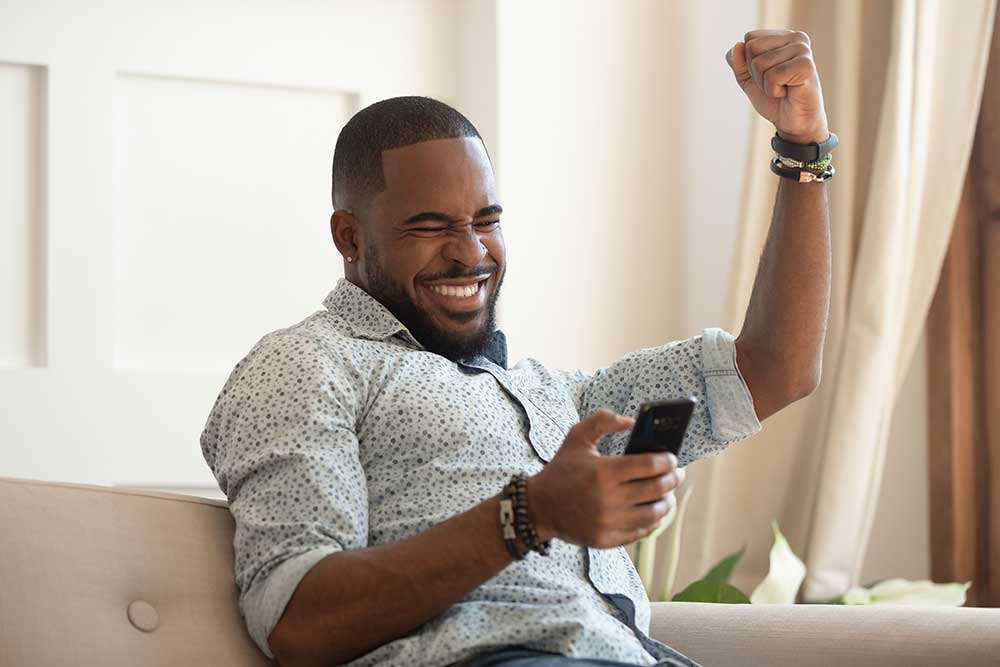Excited man holding smartphone receiving good news