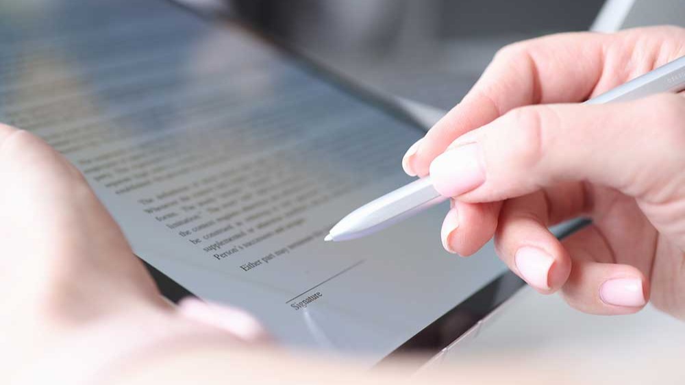 Woman hand holds stylus and puts an electronic signature in contract on tablet
