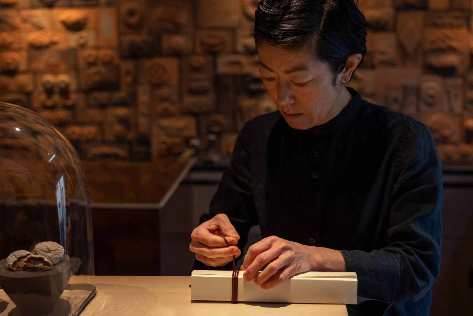 a shop assistant wrap a box of wagashi, traditional Japanese pastries, in white paper