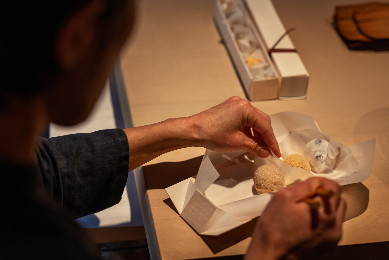 a shop assistant wrap a box of wagashi, traditional Japanese pastries, in white paper