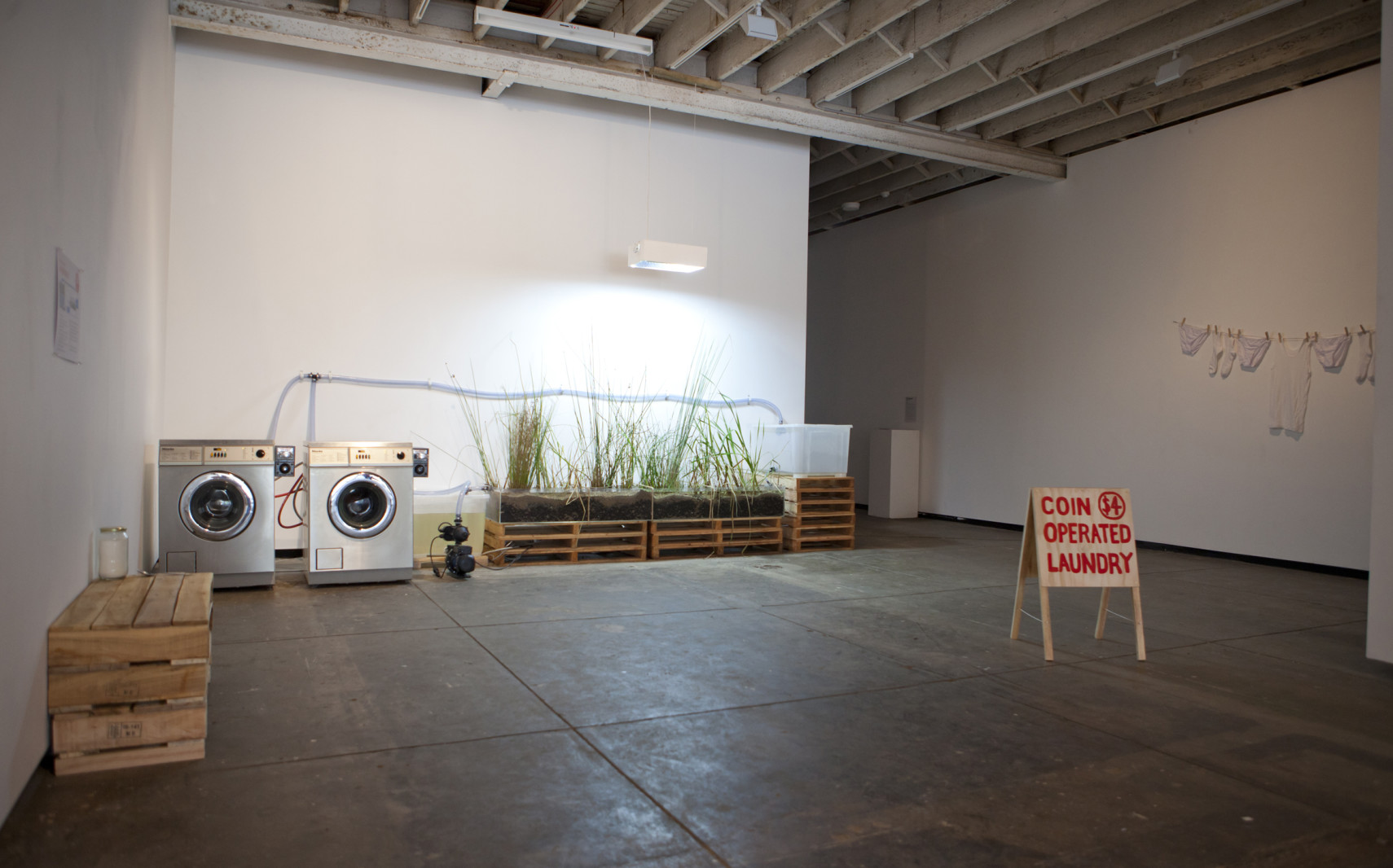 Photo of an installation with two washers wired to a planter, with a sandwich board reading 