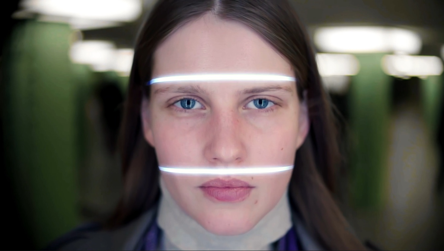 A woman has her face scanned by a ticket machine.