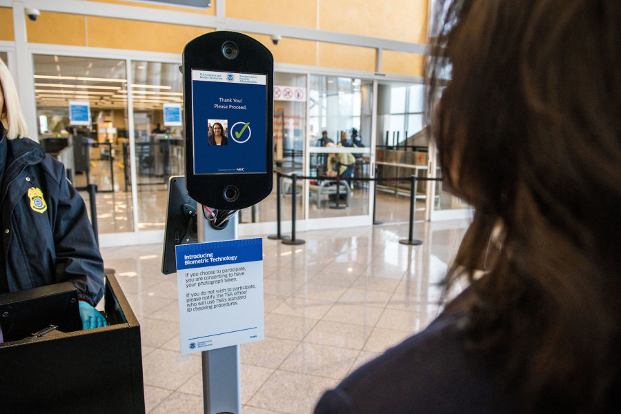A photo of a biometric scanning device and a traveler at an airport.