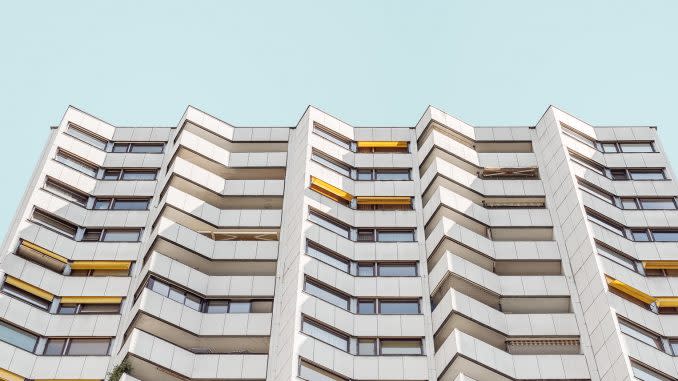 Facade of a white building with triangular outcroppings for the windows, on a blue background.