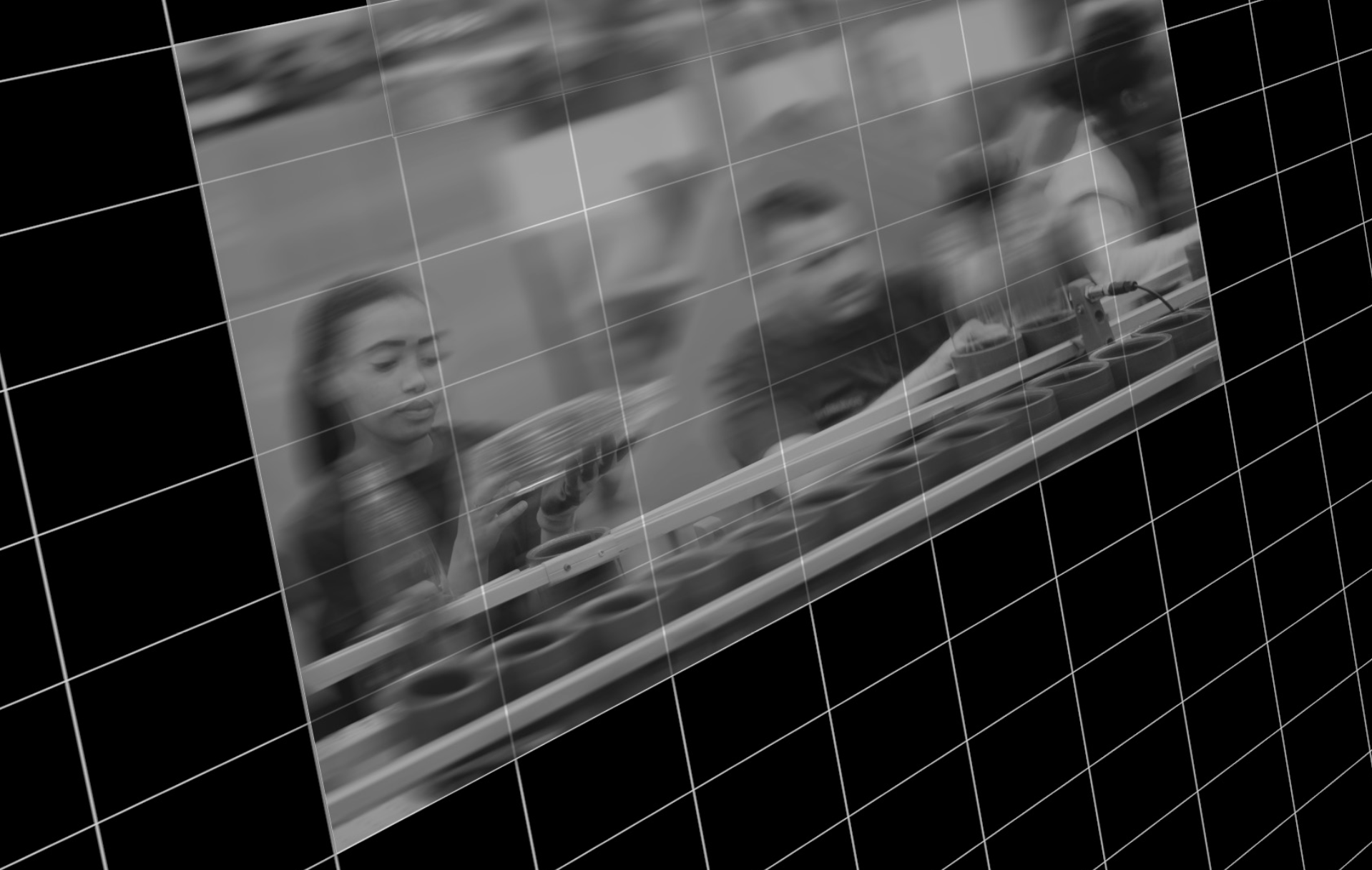 Black and white image of two people on a factory line inspecting bottles, underneath a closeup of pencils