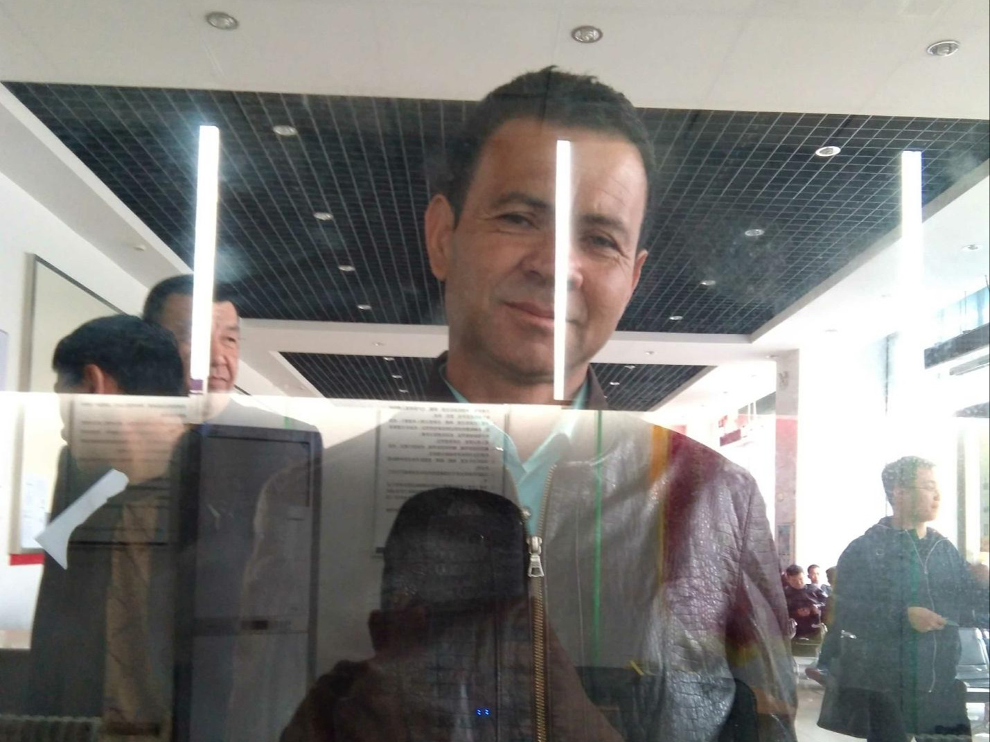 An Uyghur man has his image taken by a police officer at a face and phone scan checkpoint in 2018. 