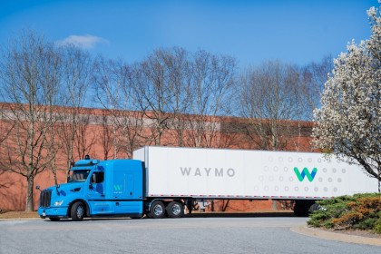 A blue, Waymo Via truck with the 4th-gen Waymo Driver and branded trailer