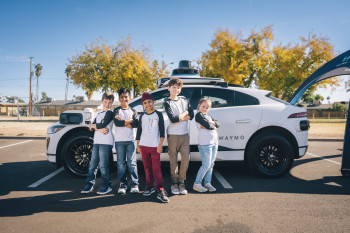 Kids from Loving Library stand in front of Waymo vehicle
