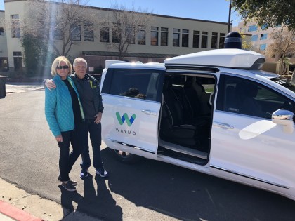A photo of Roger and Sharon in front of a white, Waymo Pacifica minivan 