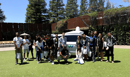 Students in front of a white, Waymo Pacifica minivan