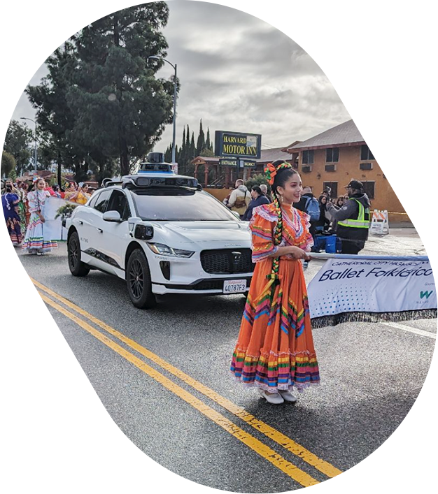 Waymo vehicle surrounded by participants of Kingdom Day Parade