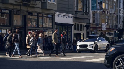 A white, Waymo vehicle yielding to pedestrians in a cross walk in San Francisco 