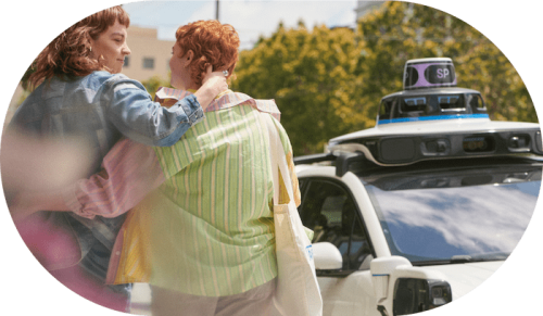 Two people approaching a Waymo car