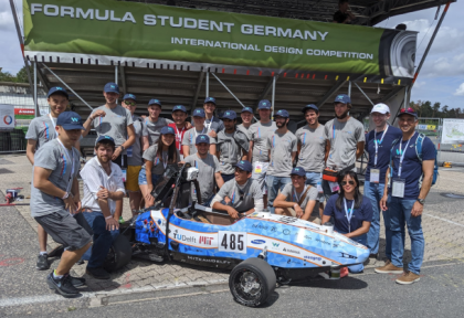 A photo of the MIT Delft Driverless Team and members of the Waymo team in front of an autonomous race car