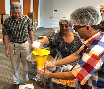 A photo of Waymonauts in hairnets funneling dry goods into bags