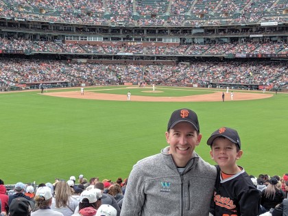 A photo of Matt Schwall and his son in San Francisco Giants hats on at the ball game