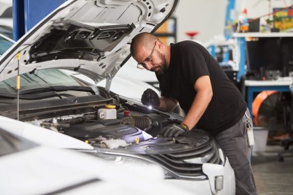 A person working under the hood of a Waymo vehicle