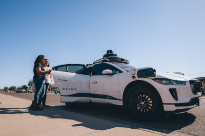 Juana and Minerva opening the door to a Waymo One autonomous ride-hailing vehicle