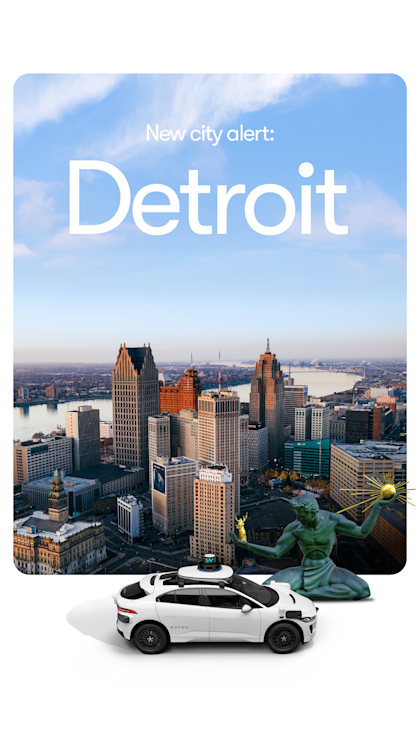A white Waymo SUV in front of the Detroit Skyline 