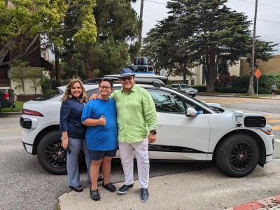 Fernando Gomez with his wife, Cynthia, and son, Oscar, in front of a Waymo One autonomous vehicle