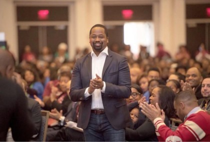 A photo of Reginald McKnight surrounded by people clapping 